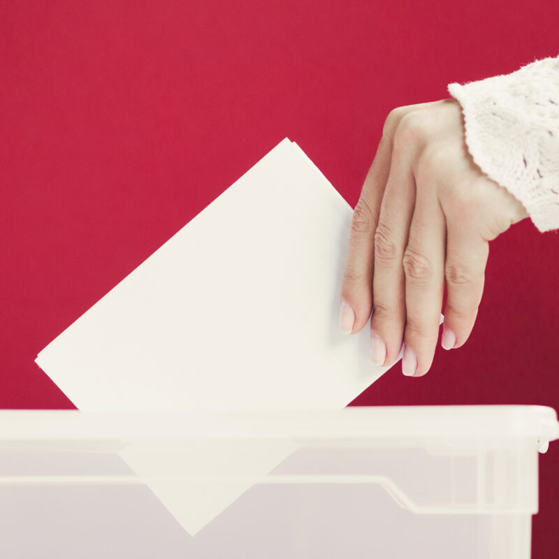 mujer introduciendo papeleta de voto en urna